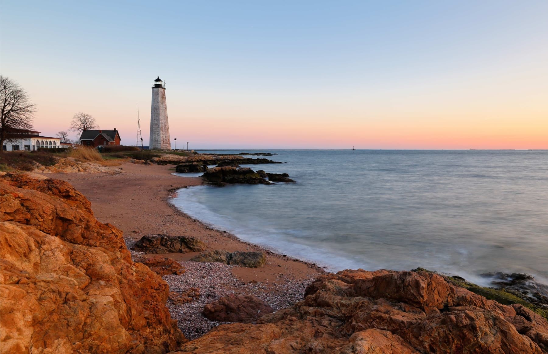 A tall white lighthouse on a rocky shoreline