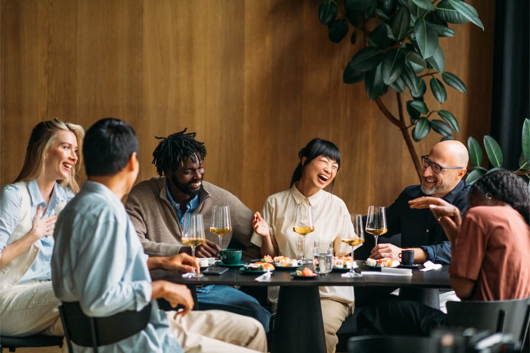 A group of friends laughing & enjoying drinks around a table