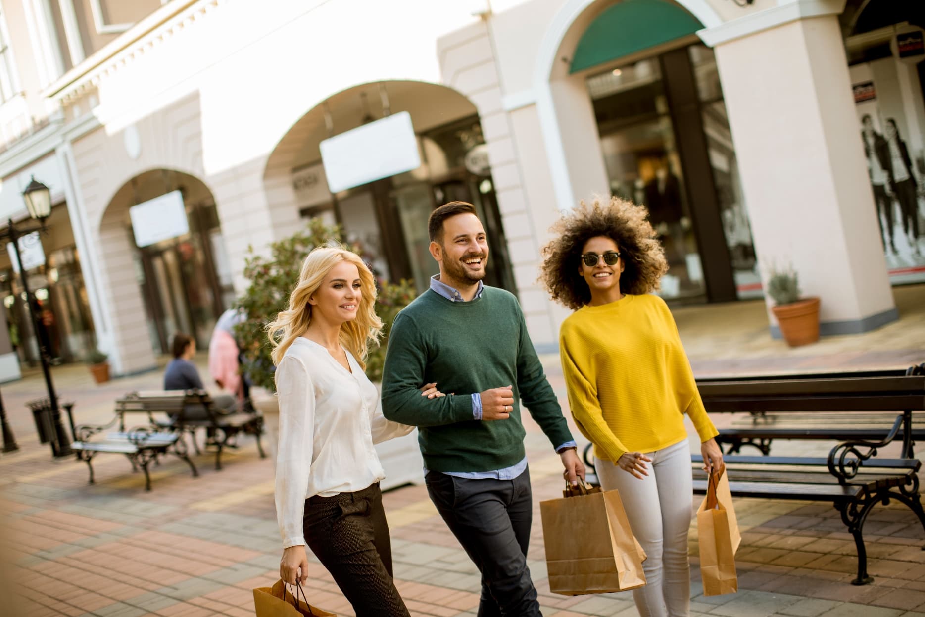 Three friends walking outdoors with shopping bags